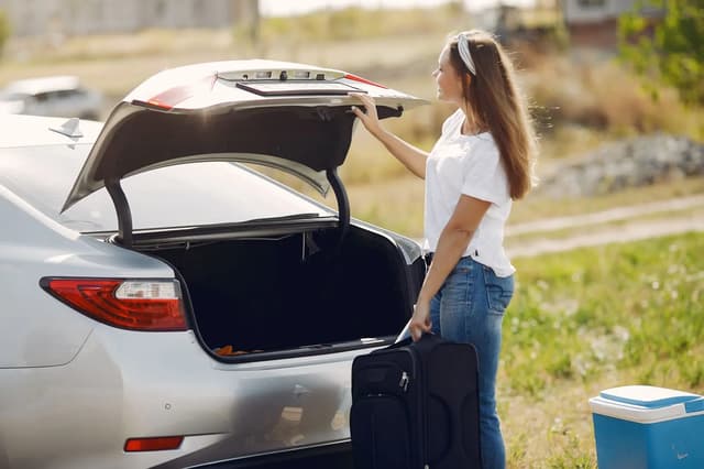Traveler loading luggage into a rental car